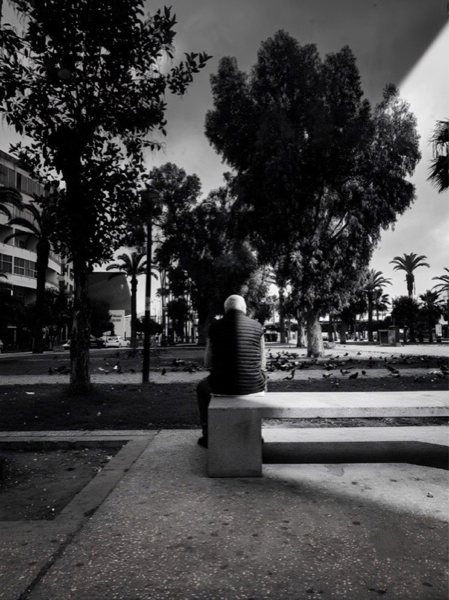 Une personne seule sur un banc, en noir et blanc